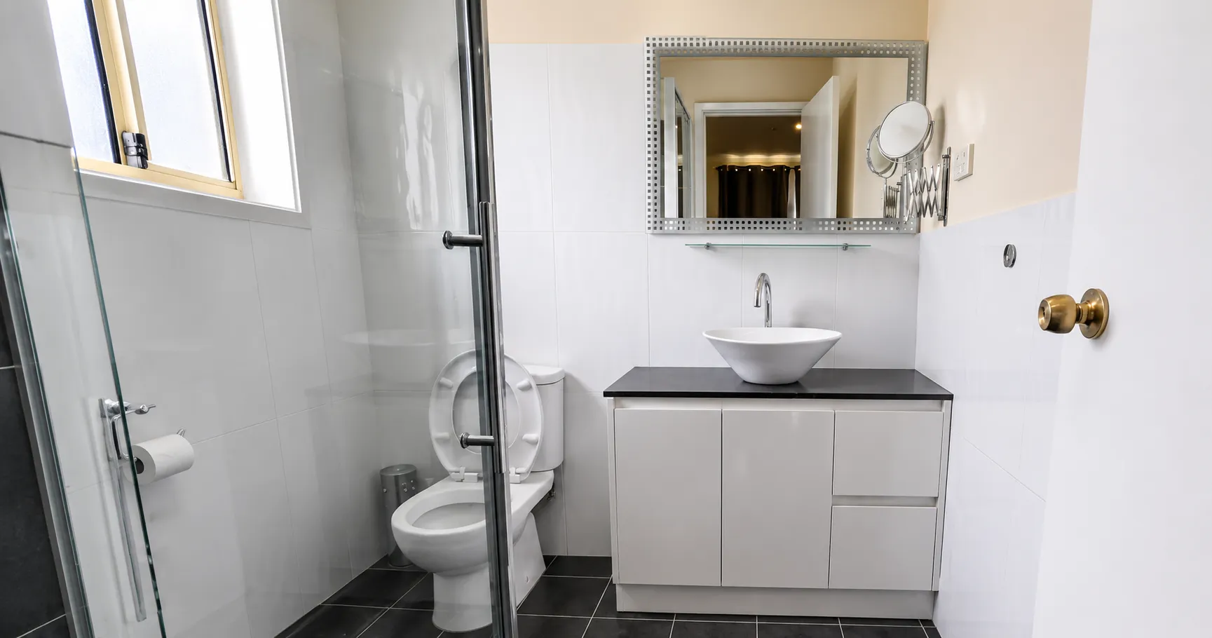Renovated bathroom — dark tile floor, glass shower, modern vanity